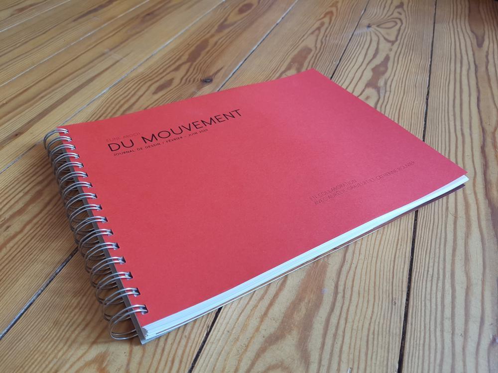 Livre sur un parquet, couverture rouge, avec le titre "Du mouvement" de Coraline Grandin et Eline Aroch